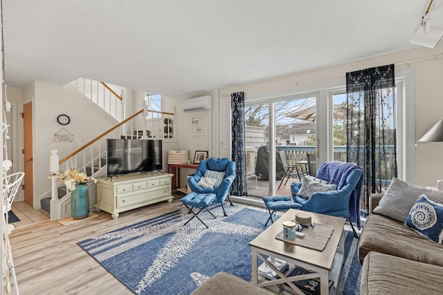 living room featuring a textured ceiling, light hardwood / wood-style floors, and a wall mounted AC