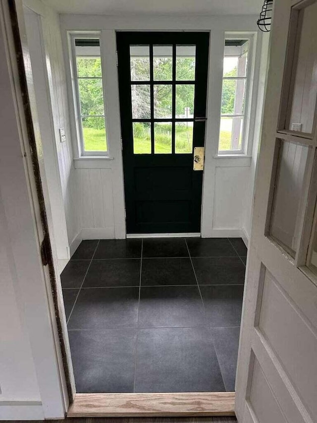 entryway with plenty of natural light and dark tile patterned floors