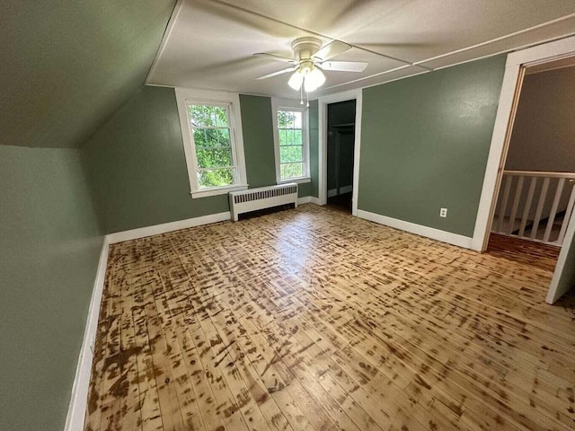 additional living space with hardwood / wood-style flooring, ceiling fan, lofted ceiling, and radiator