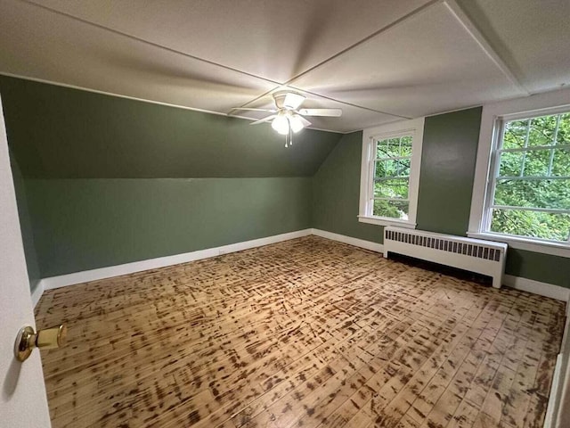 additional living space with wood-type flooring, radiator, lofted ceiling, and ceiling fan