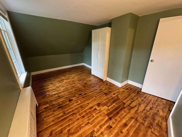 additional living space with dark hardwood / wood-style floors and vaulted ceiling