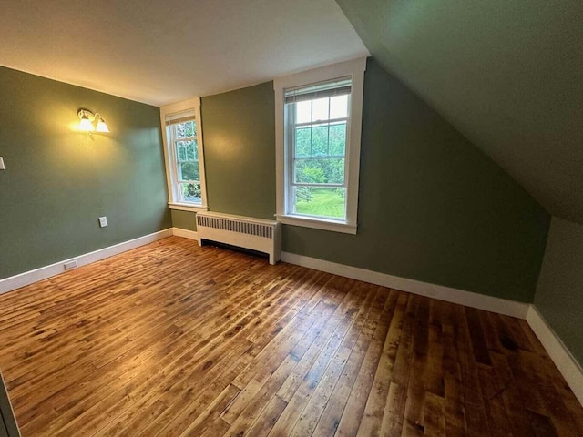 bonus room with radiator, wood-type flooring, and lofted ceiling