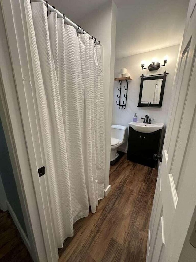 bathroom with hardwood / wood-style flooring, vanity, and toilet