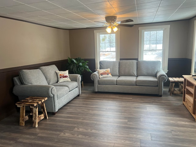 living room with dark wood-type flooring, ceiling fan, and a healthy amount of sunlight