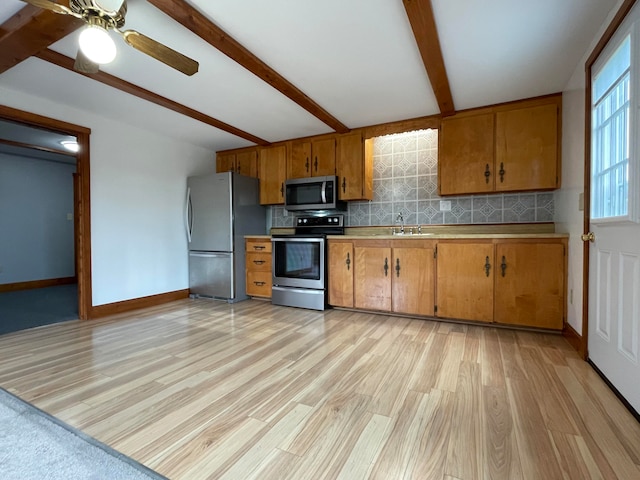 kitchen featuring decorative backsplash, appliances with stainless steel finishes, light wood-type flooring, sink, and beamed ceiling