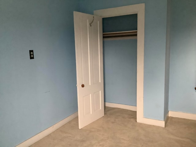 unfurnished bedroom featuring a closet and light colored carpet