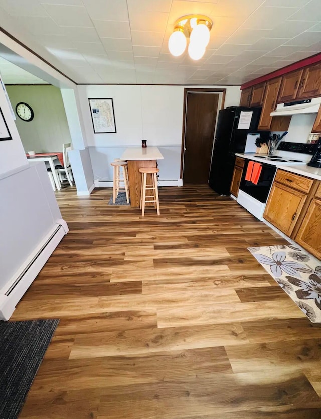 kitchen featuring a breakfast bar, a baseboard radiator, dishwashing machine, light hardwood / wood-style floors, and black fridge