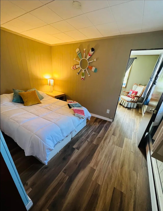 bedroom with hardwood / wood-style floors and wood walls