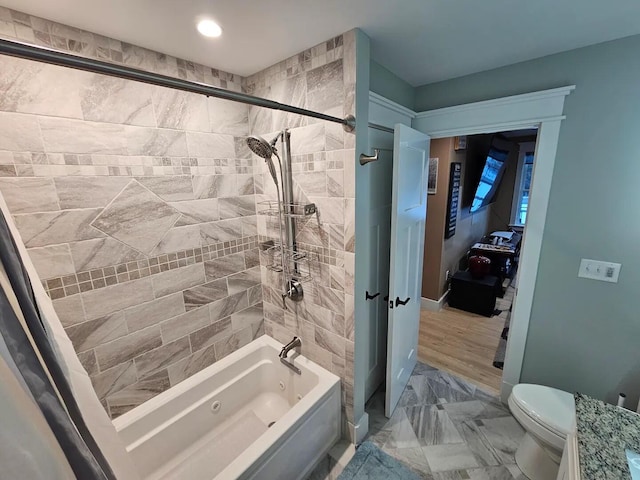 bathroom with wood-type flooring, tiled shower / bath combo, and toilet