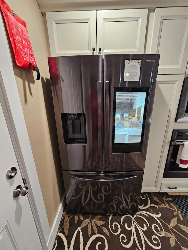 kitchen with wall oven, black fridge, and white cabinetry