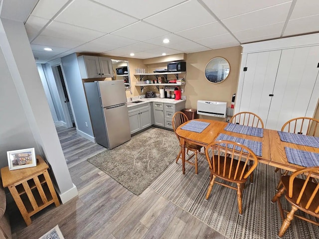 kitchen with a paneled ceiling, gray cabinets, stainless steel refrigerator, and light hardwood / wood-style flooring