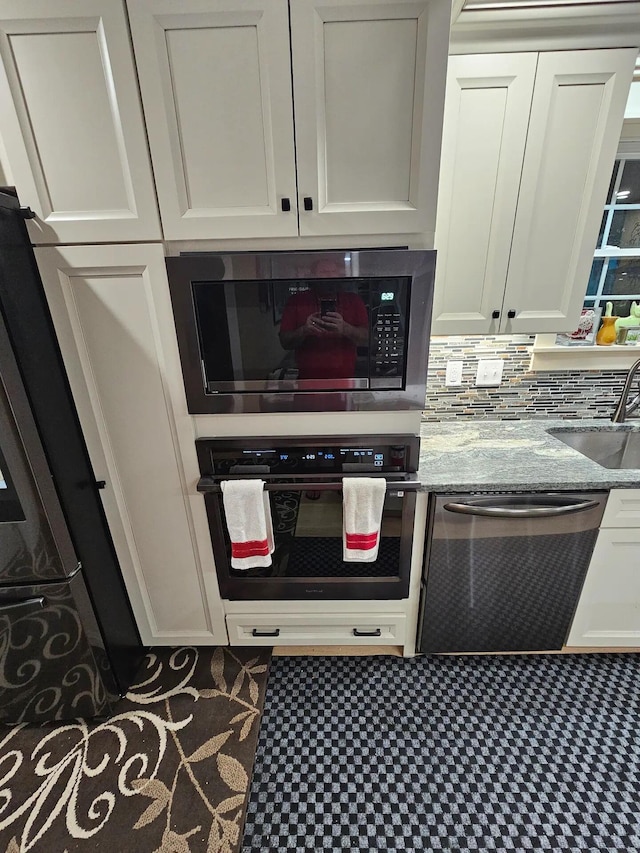 kitchen with backsplash, sink, light stone counters, white cabinetry, and stainless steel appliances