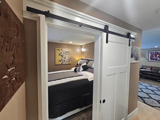 bedroom with a barn door and light wood-type flooring