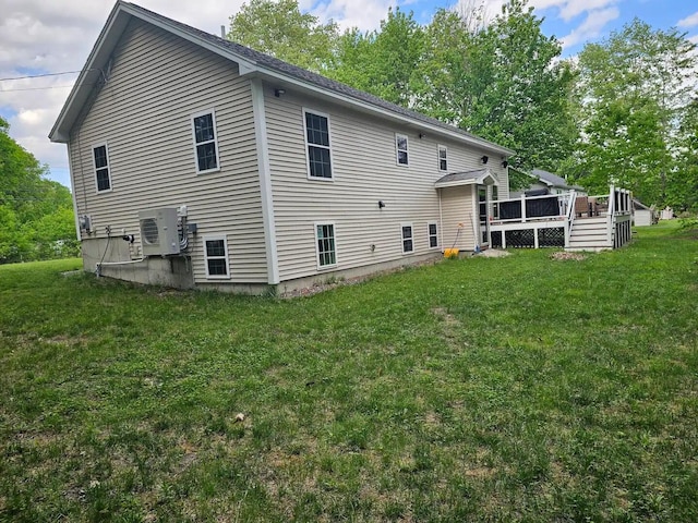 rear view of house with ac unit, a yard, and a wooden deck