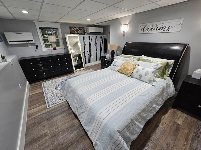 bedroom featuring a wall mounted air conditioner, a drop ceiling, and dark hardwood / wood-style floors