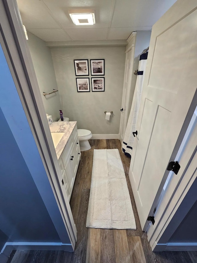 bathroom featuring a paneled ceiling, vanity, toilet, and wood-type flooring