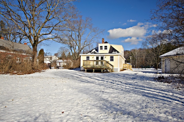 snow covered back of property with a deck