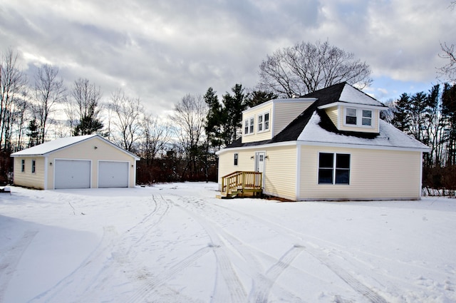 snow covered property featuring an outdoor structure and a garage