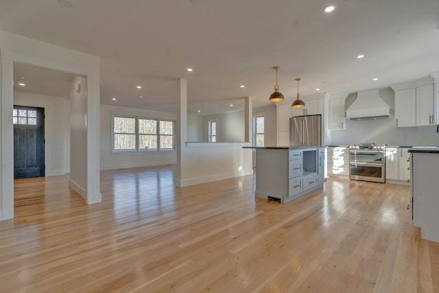 kitchen featuring a center island, stainless steel appliances, premium range hood, pendant lighting, and white cabinets