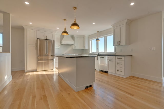 kitchen with premium range hood, white cabinets, hanging light fixtures, light wood-type flooring, and stainless steel appliances