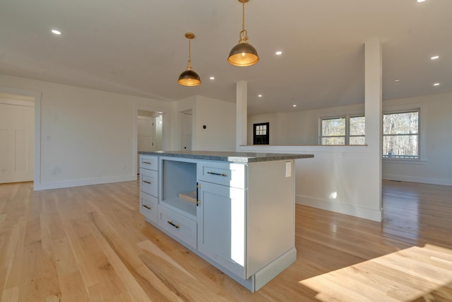 kitchen featuring light wood-type flooring, a center island, white cabinetry, and hanging light fixtures