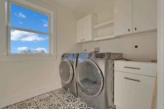 laundry room with washing machine and dryer, light tile patterned floors, and cabinets