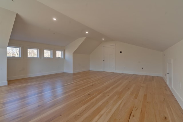 additional living space with light hardwood / wood-style flooring and lofted ceiling