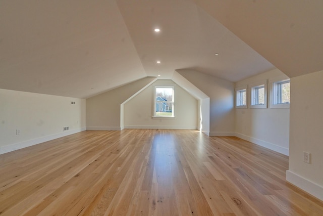 additional living space with light hardwood / wood-style floors and lofted ceiling