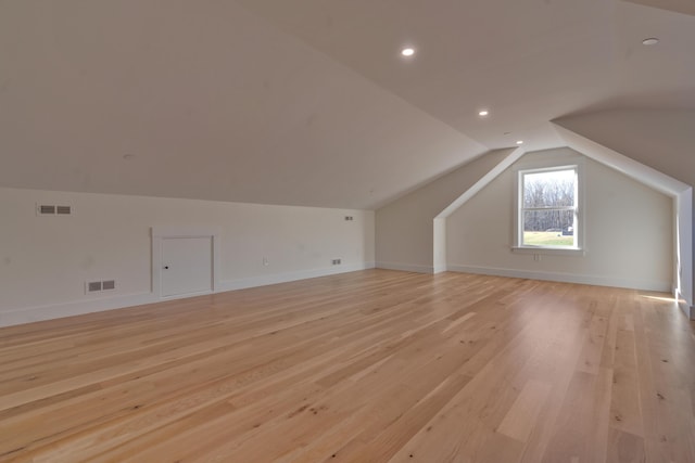 additional living space with light hardwood / wood-style floors and lofted ceiling