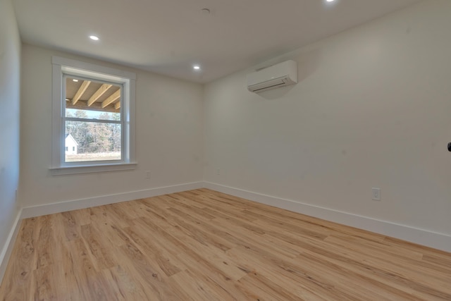 unfurnished room with a wall mounted air conditioner and light hardwood / wood-style flooring