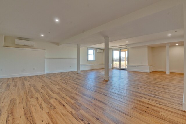 spare room featuring a wall unit AC and light hardwood / wood-style flooring