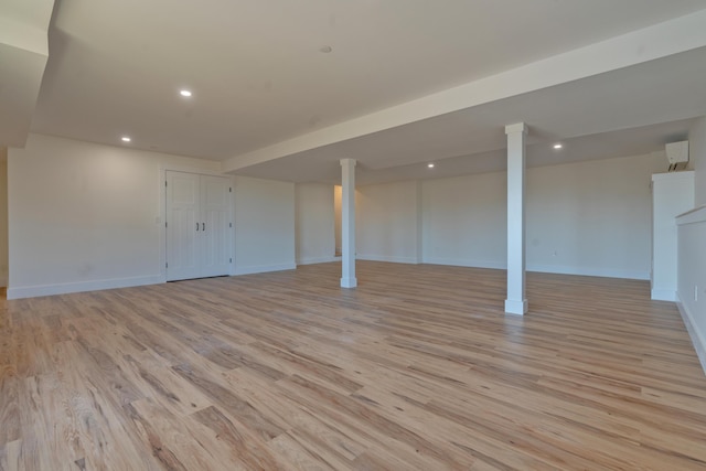 basement featuring an AC wall unit and light wood-type flooring