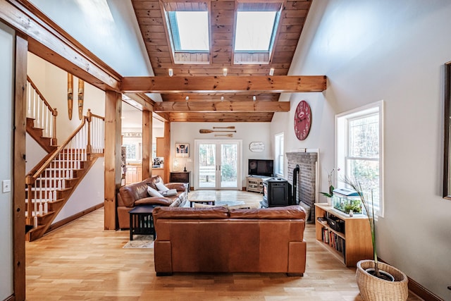 living room featuring stairway, a towering ceiling, baseboards, and light wood finished floors