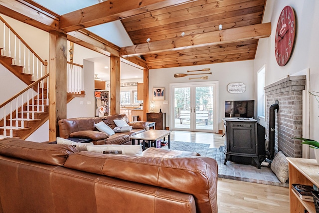 living room with light wood finished floors, stairway, lofted ceiling with beams, wooden ceiling, and a wood stove