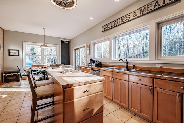 kitchen with a sink, dishwasher, light tile patterned floors, and butcher block countertops