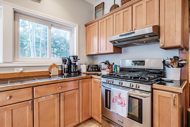 kitchen with under cabinet range hood, stainless steel range with gas stovetop, and light brown cabinetry