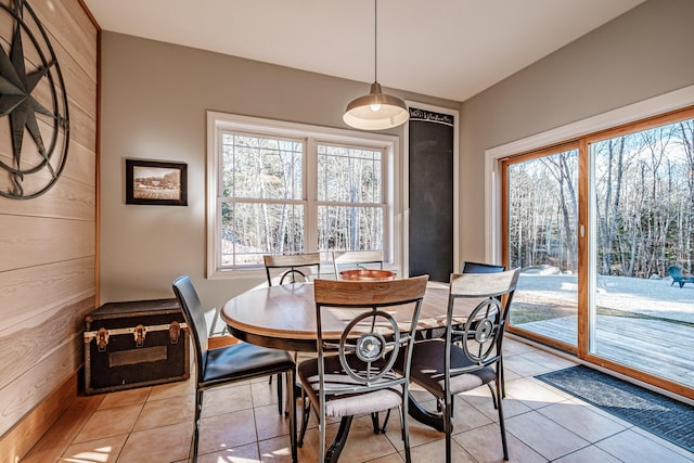 dining space featuring wooden walls and light tile patterned floors