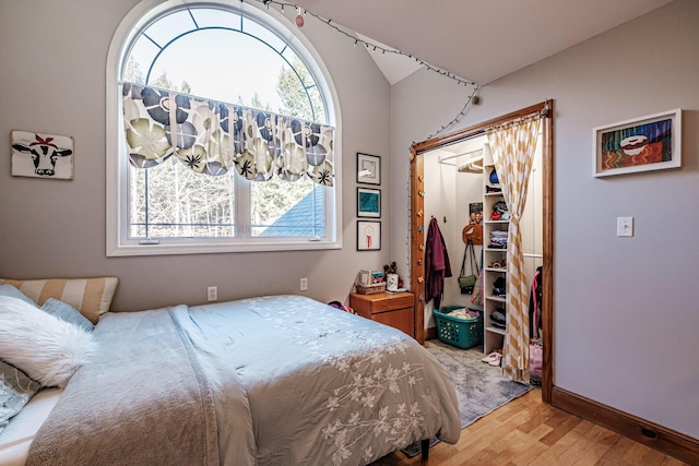 bedroom with baseboards, lofted ceiling, a closet, and light wood finished floors