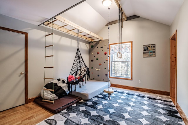 workout area with baseboards, wood finished floors, and vaulted ceiling