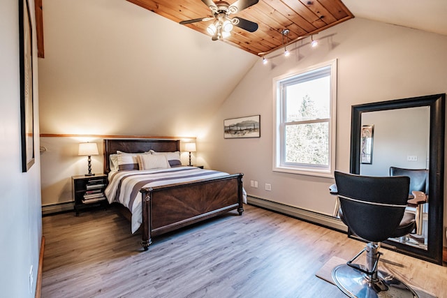 bedroom with baseboards, wood finished floors, lofted ceiling, and a baseboard radiator