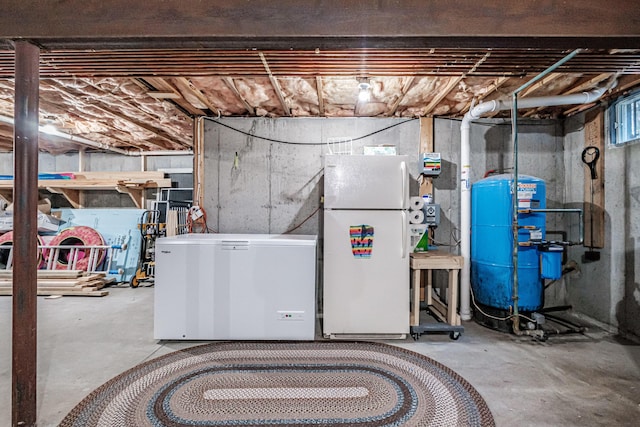 unfinished basement with fridge and freestanding refrigerator