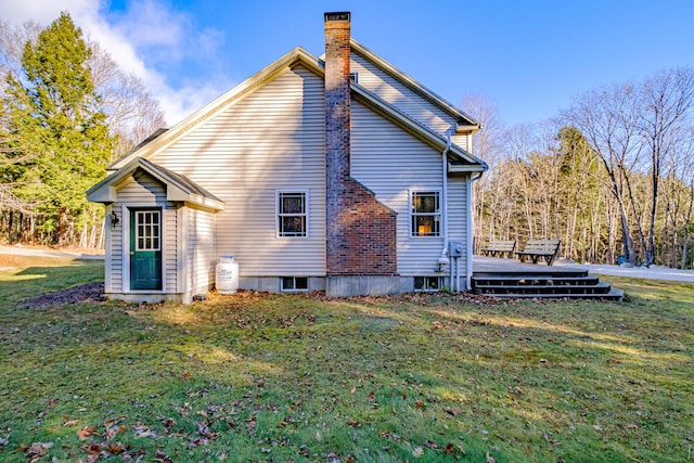 back of property featuring a deck, a lawn, and a chimney