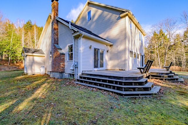 back of property with a wooden deck, a yard, and a chimney