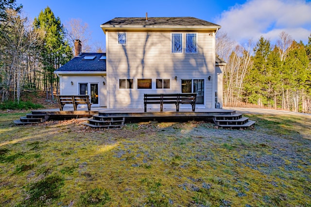 rear view of house with a wooden deck, a chimney, and a yard