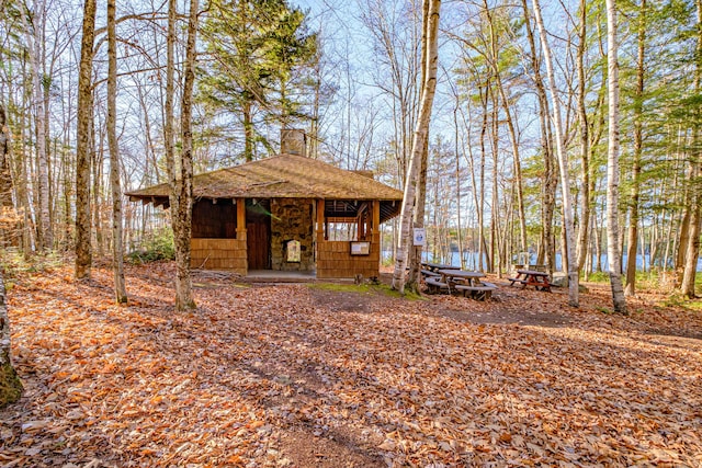 view of front facade featuring an outdoor structure and roof with shingles