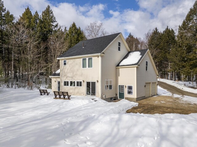 snow covered rear of property featuring a garage