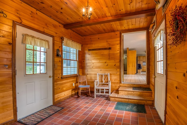 entryway featuring wood walls, dark tile patterned floors, beamed ceiling, and wooden ceiling