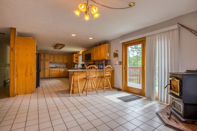 kitchen with kitchen peninsula, a kitchen breakfast bar, black appliances, a chandelier, and light tile patterned flooring