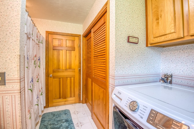 laundry area with cabinets, a textured ceiling, washer / clothes dryer, and light tile patterned flooring