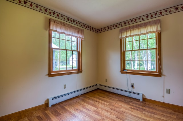 unfurnished room featuring light hardwood / wood-style floors, a wealth of natural light, and a baseboard heating unit